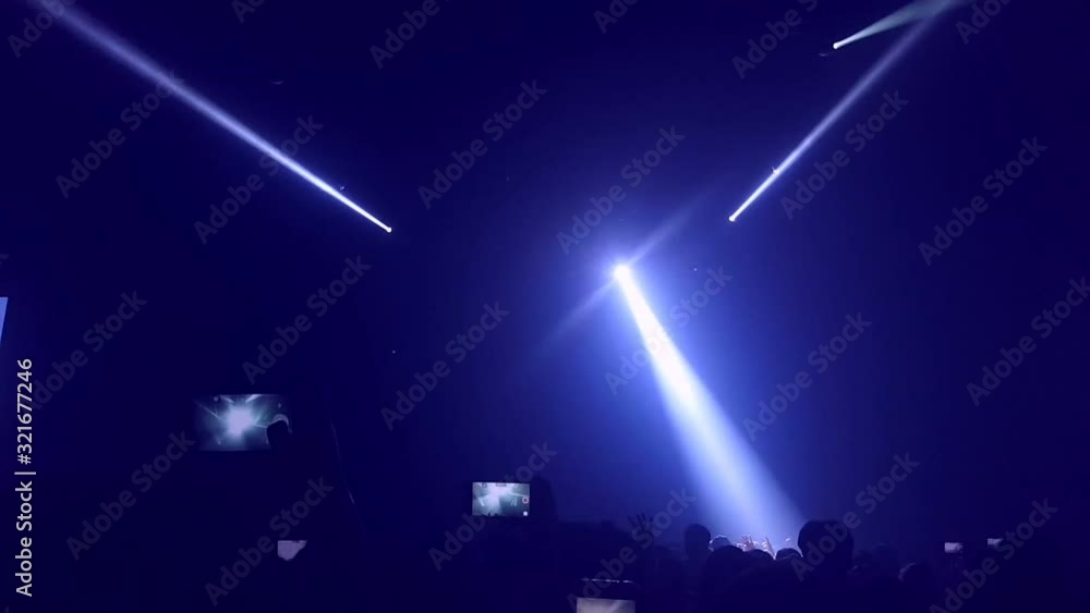 Happy people dance in nightclub party concert and listen to music from DJ on the stage in background. Cheerful crowd celebrate Christmas and New Year party 2018. Young people lifestyle and nightlife.