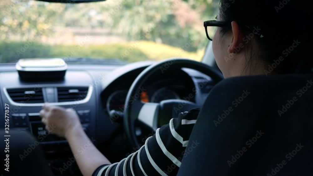 Young woman driving in a car and turning button of radio, dancing having fun in country street on sunny day. Young woman driving in a car and turning button of radio, dancing having fun in country street on sunny day.