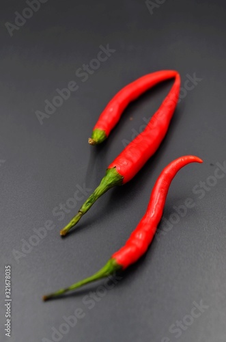 Three red peppers on a black background