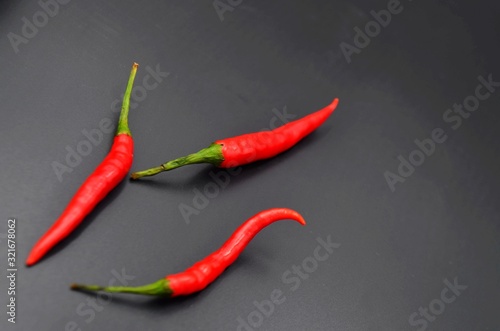 Three red peppers on a black background