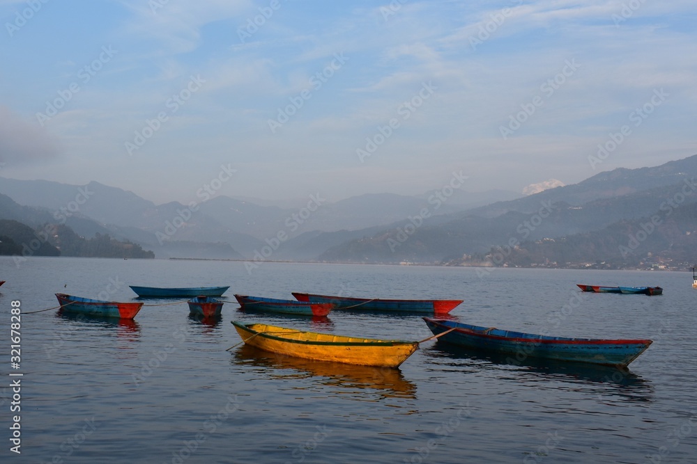 yellow boat the others colour in mountain ranges background with fog and blue sky .phewa lake nepal