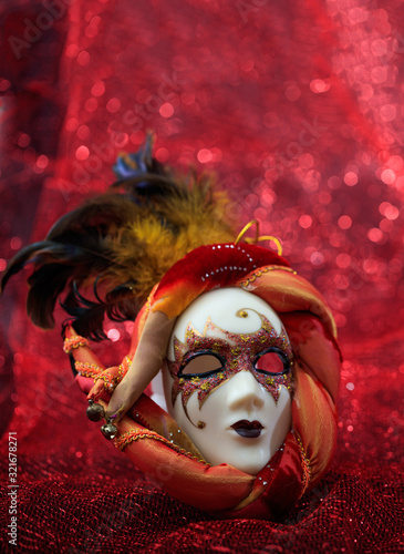 Fototapeta Naklejka Na Ścianę i Meble -  Carnival mask female theatrical face against red bokeh background. Festive party celebration