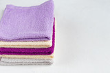 Terry towels for beauty and health. A stack of multi-colored towels lies on a white background. Lifestyle, housework.