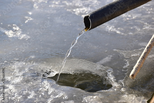 acqua che scorre da un tubo di un abeveratoio ghiacciato