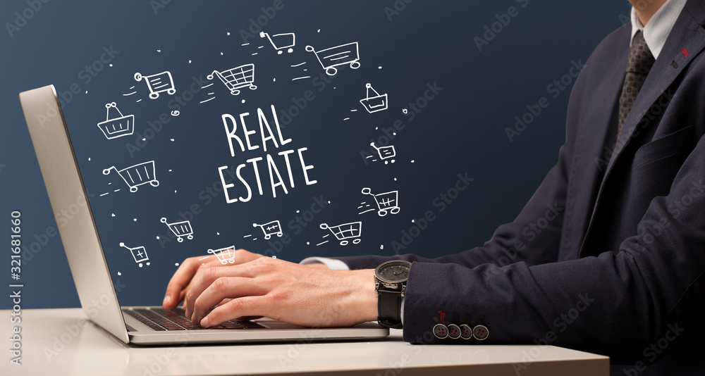 Businessman working on laptop with REAL ESTATE inscription, online shopping concept Businessman working on laptop with REAL ESTATE inscription, online shopping concept