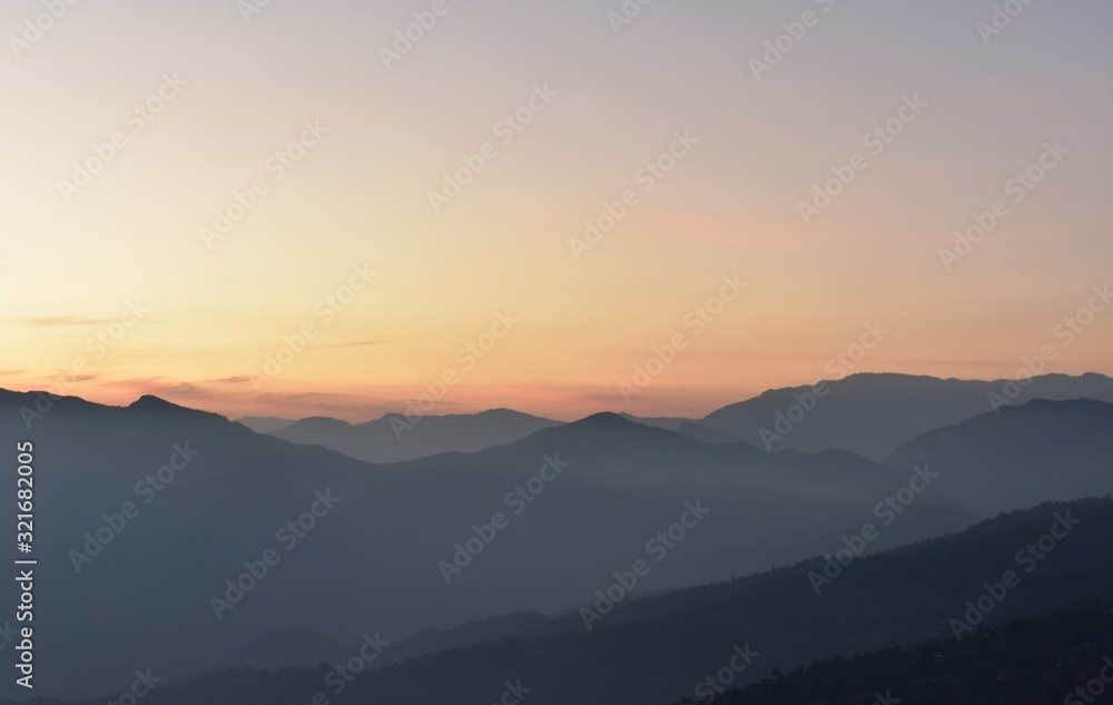 sunset in the mountains with orange sky and mist