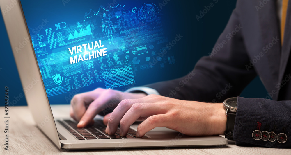 Businessman working on laptop with VIRTUAL MACHINE inscription, cyber technology concept Businessman working on laptop with VIRTUAL MACHINE inscription, cyber technology concept