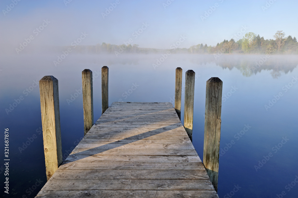 Naklejka premium Landscape of dock and foggy, spring shoreline of Whitford Lake, Fort Custer State Park, Michigan, USA