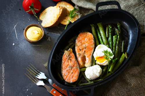 Green asparagus, grilled salmon and poached eggs. Healthy food on rustic wooden background. Copy space.