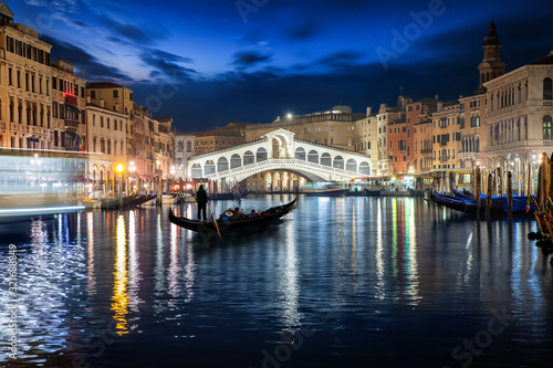  Die beleuchtete Rialto Brücke in Venedig, Italien, mit vorbeifahrender Gondel bei Nacht