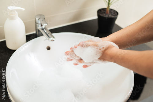 Man washing hands with soap under running water