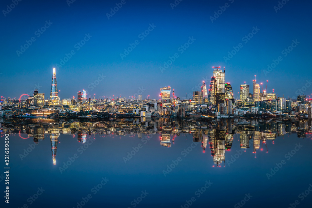 Weites Panorama der Skyline von London, Großbritannien, am Abend mit Reflektionen im Wasser