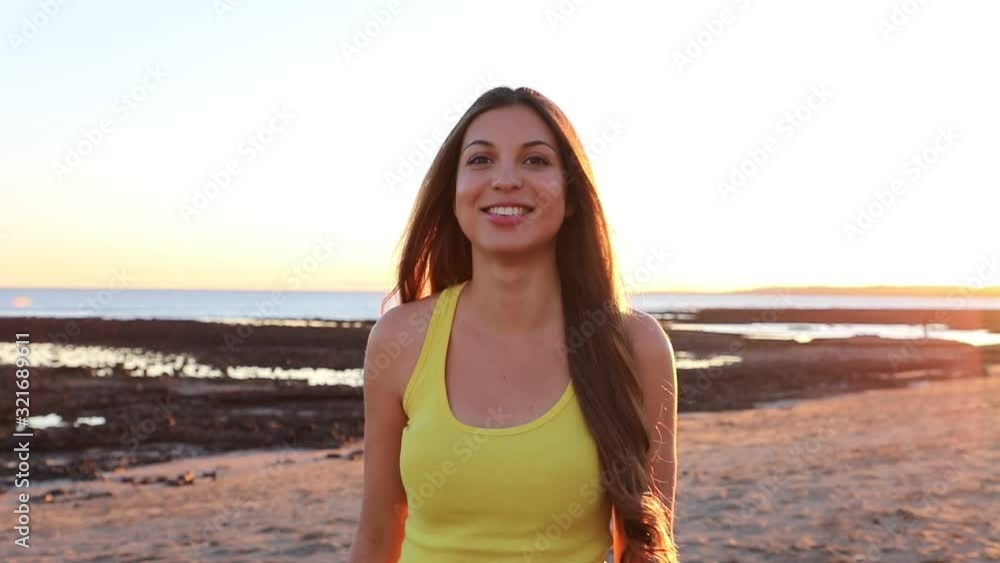 Portrait of young woman smiling on camera on the beach at sunset. Slow motion. Portrait of young woman smiling on camera on the beach at sunset. Slow motion.