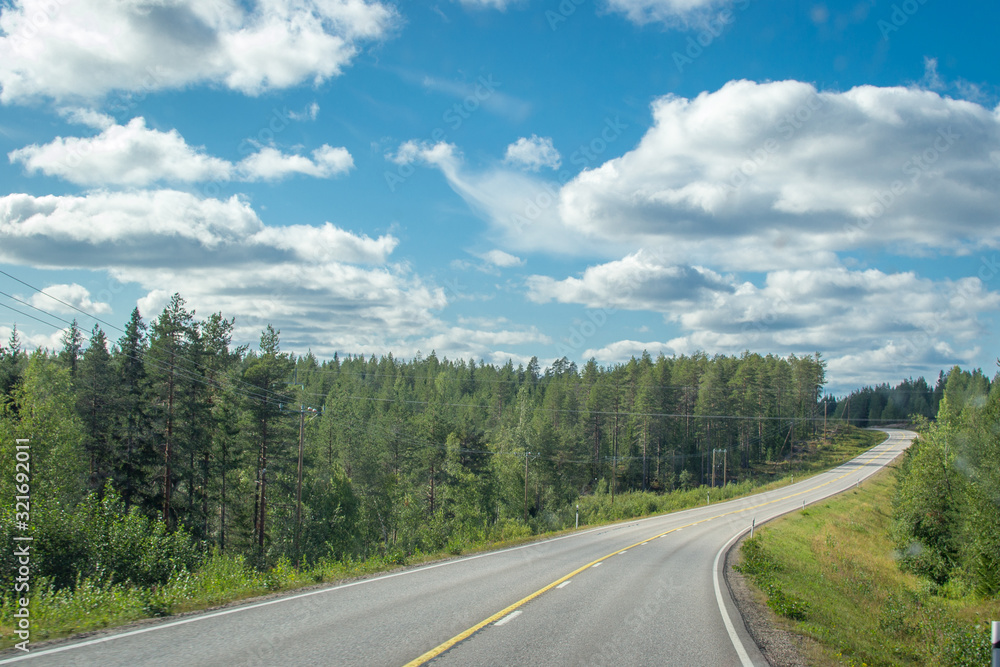 Finland. View of a scenic road passing through a forest. Beautiful Scandinavian landscape.