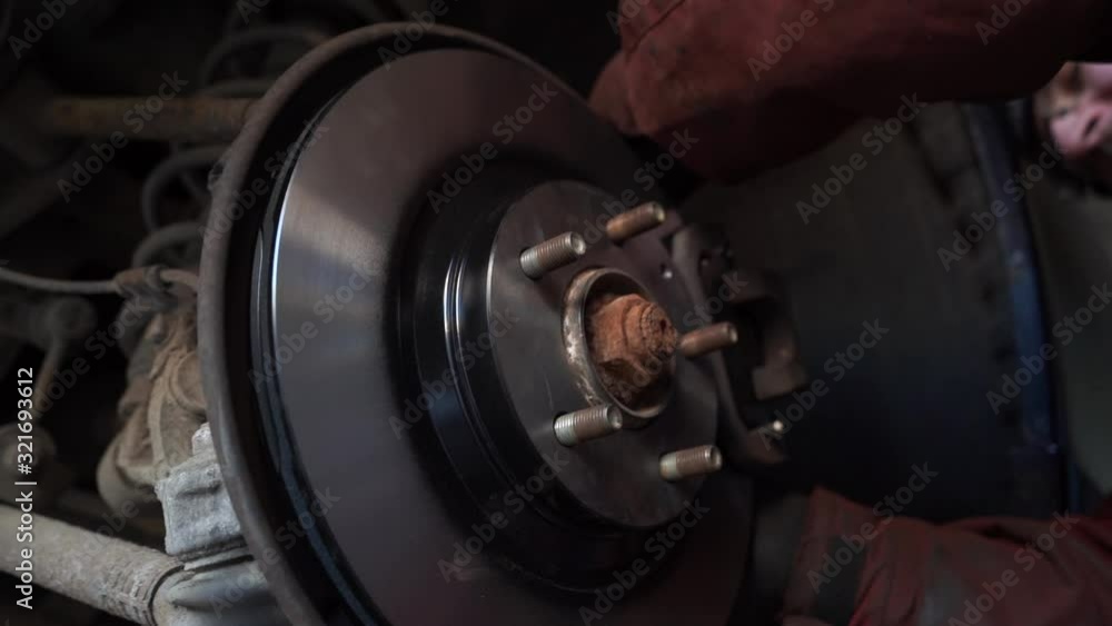 Car mechanic replacing car wheel brake shoes of lifted automobile at repair service station. Slow motion. Car mechanic replacing car wheel brake shoes of lifted automobile at repair service station. Slow motion.
