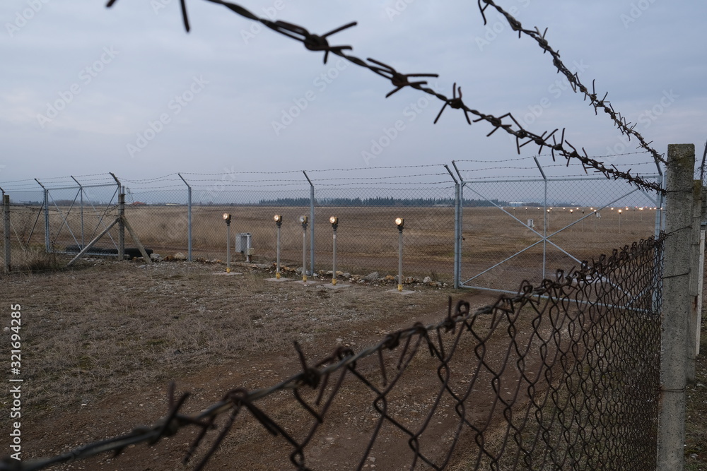 A barbed wire fence with concrete post on the airport Podgorica, Montenegro A barbed wire fence with concrete post on the airport Podgorica, Montenegro