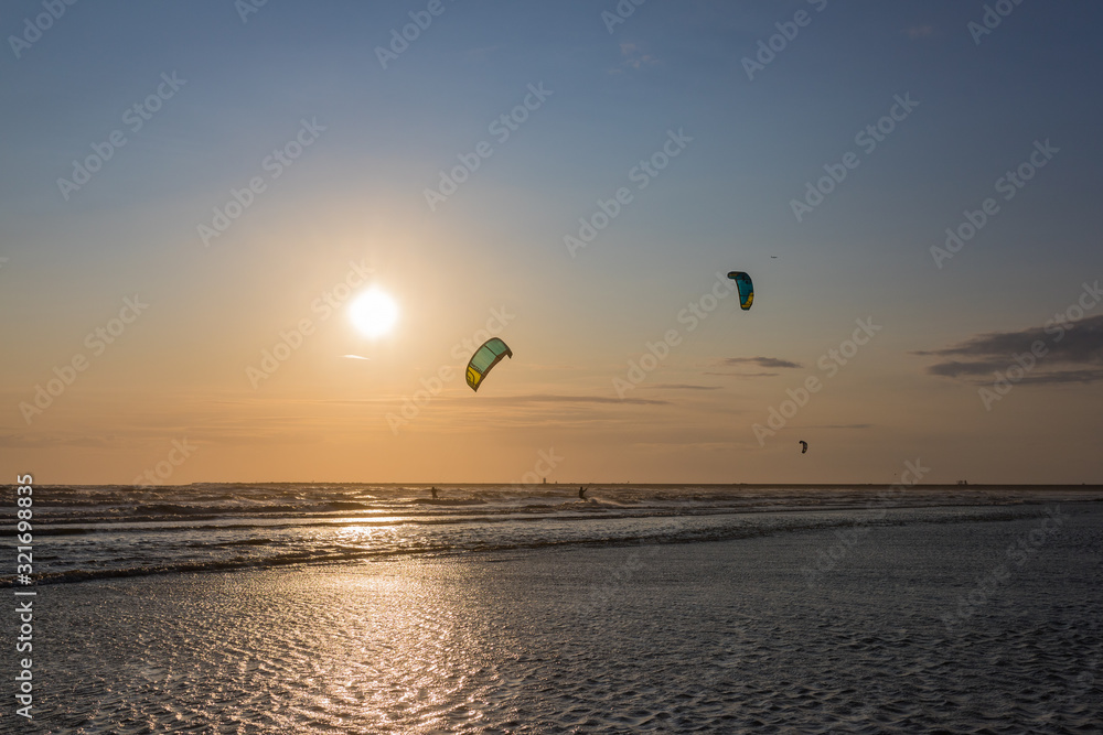 2 surfers, in the background the sunset, a surfer jumps high