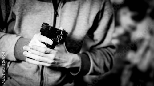 Man holding pistol at the "low ready" position in black and white