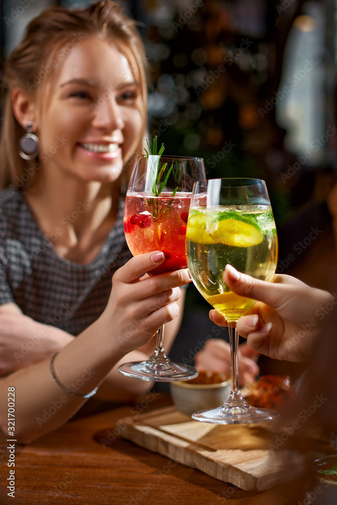 Two girls drink cocktails with ice red and yellow colors. Extremely bright colors. The atmosphere of joy. Selective focus.