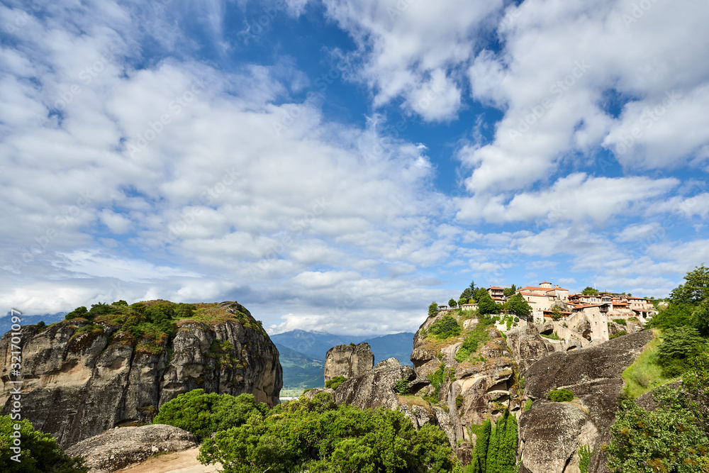 Amazing Meteora Monastery in Greece. Fantastic view at mountains and green forest against epic blue sky with clouds. UNESCO