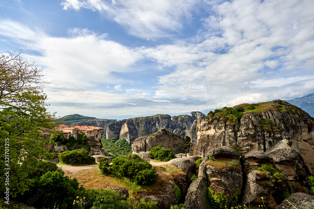 Amazing Meteora Monastery in Greece. Fantastic view at mountains and green forest against epic blue sky with clouds. UNESCO