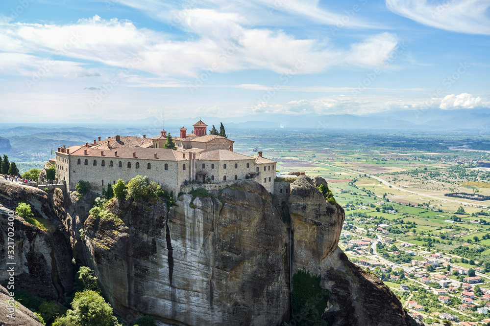 Amazing Meteora Monastery in Greece. Fantastic view at mountains and green forest against epic blue sky with clouds. UNESCO