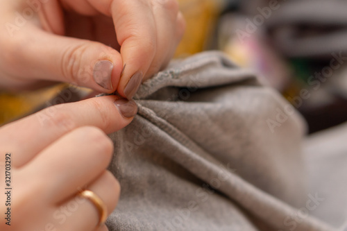 female hands sew clothes with a needle