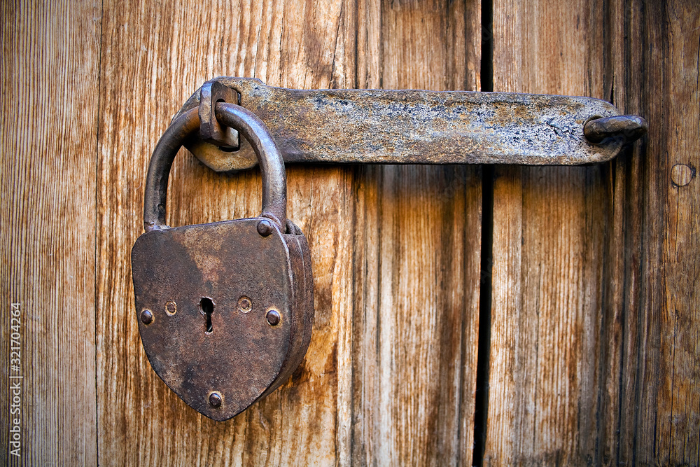 Iron lock with heart-shaped padlock on old wooden door Iron lock with heart-shaped padlock on old wooden door