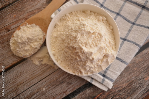 farina bianca di grano in ciotola su tavolo di legno e cucchiaio di legno da cucina ingrdiente per cucinare