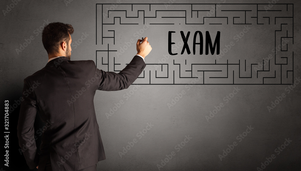 businessman drawing maze with EXAM inscription, business education concept businessman drawing maze with EXAM inscription, business education concept
