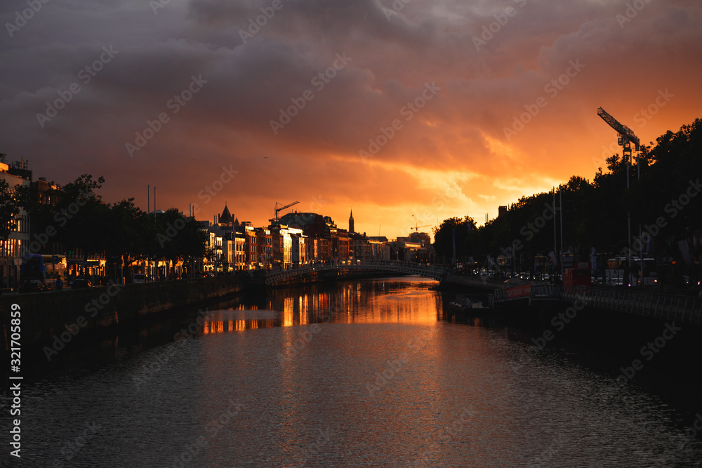 Dublin's cityscape during a colorful sunset with clouds and seagulls over Liffey river