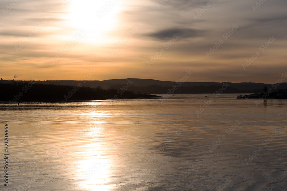 Obraz premium Blick auf eine Flusslandschaft in Norwegen in der Abenddämmerung im Gegenlicht mit Textfreiraum