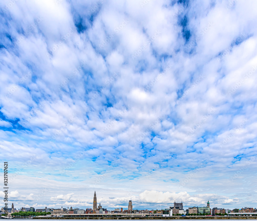 Skyline of downtown Antwerp (Antwerpen), Belgium, as seen from the opposite side of the River Scheldt, under a blue sky with clouds