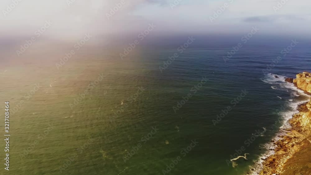 High angle pan from calm sea with cliffs to small Portugese town on top of hill. Filmed in Nazare, Portugal High angle pan from calm sea with cliffs to small Portugese town on top of hill. Filmed in Nazare, Portugal