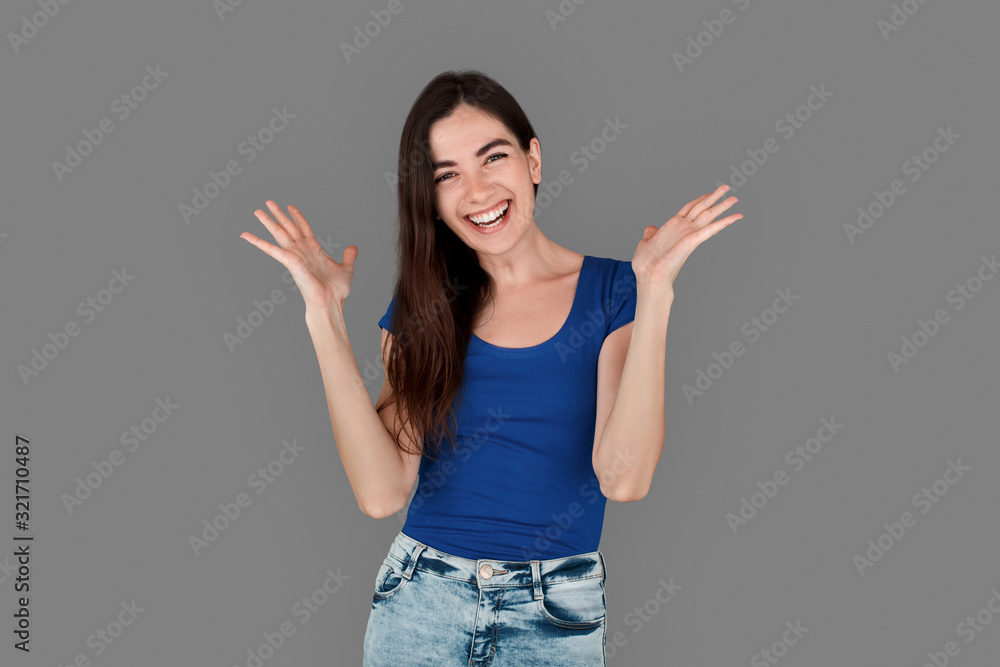 Young girl studio standing isolated on grey hands aside laughing playful Young girl studio standing isolated on grey hands aside laughing playful