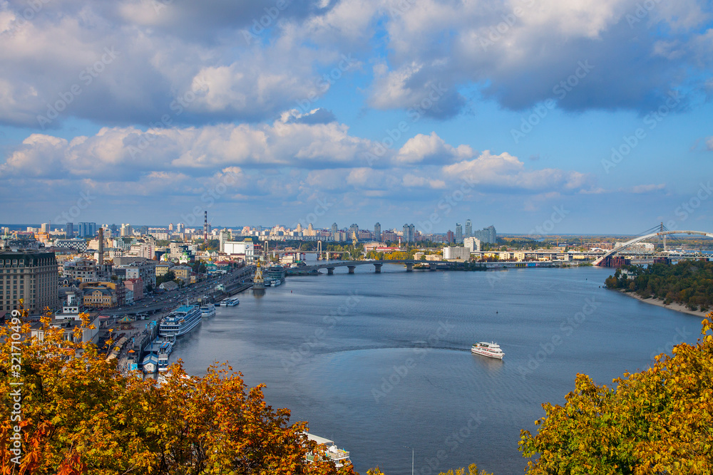 City of Kiev, Ukraine. View of the Podil. City landscape overlooking the Dnieper river, parks and builds. Fluffy clouds and sunny autumn day.