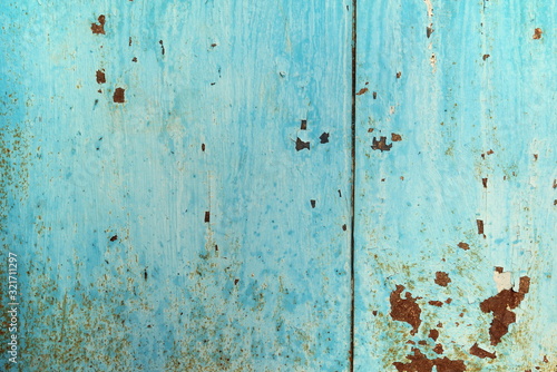 Old iron sheet with peeling blue paint and rusty spots.