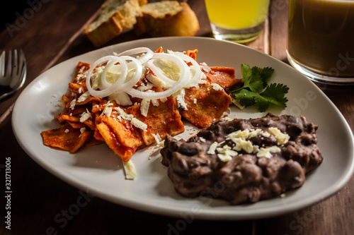 Plato de Chilaquiles y frijoles caseros con crema y queso cotija cafe y jugo desayuno tradicional mexicano
