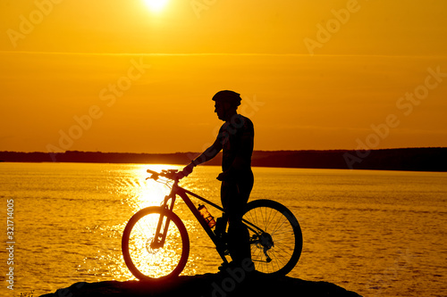 Silhouette of a bike on sky background on sunset on a mountain top.