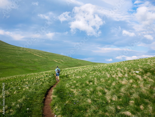 man goes on tourist hiking alpine trail in Russia. Active recreation, healthy lifestyle. Enjoys scenic view. Beautiful nature. Travel, adventure. Sense of freedom. photo