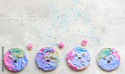 Cute toasts with colorful cream cheese spread on a light grey stone background. Ideas for kid’s food. Copy space, top view.