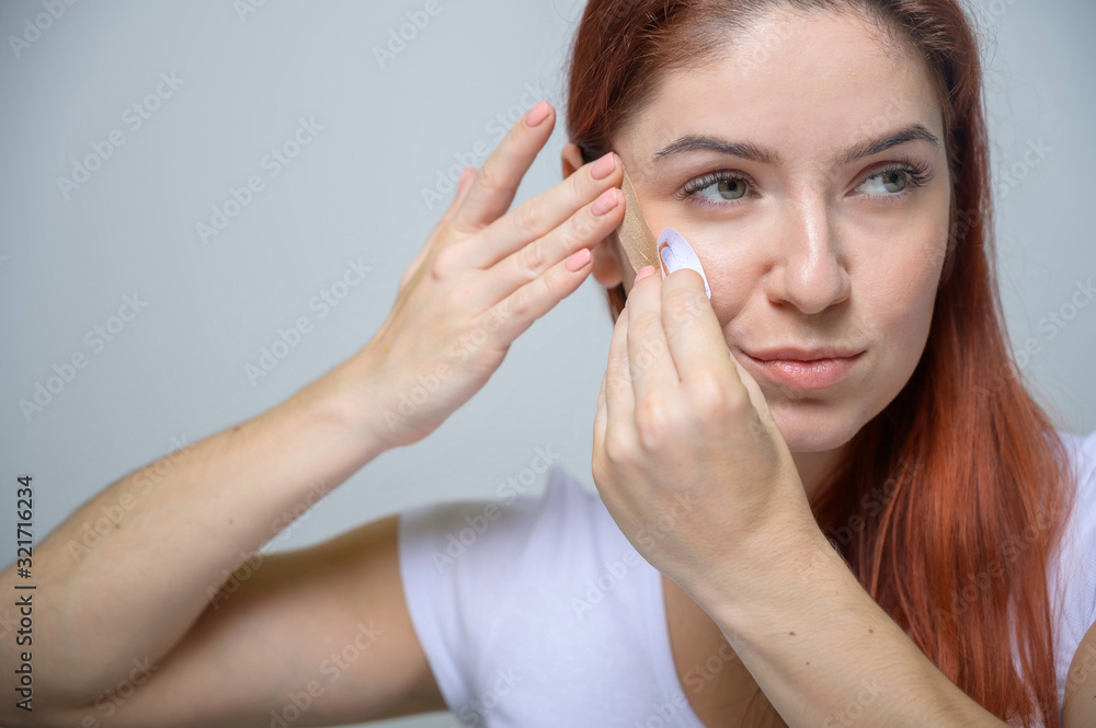 Portrait Beautiful Red-haired Woman with Kinesiology Facelift Tape. Girl beautician puts on face kinesio tape for facelift. Portrait Beautiful Red-haired Woman with Kinesiology Facelift Tape. Girl beautician puts on face kinesio tape for facelift.