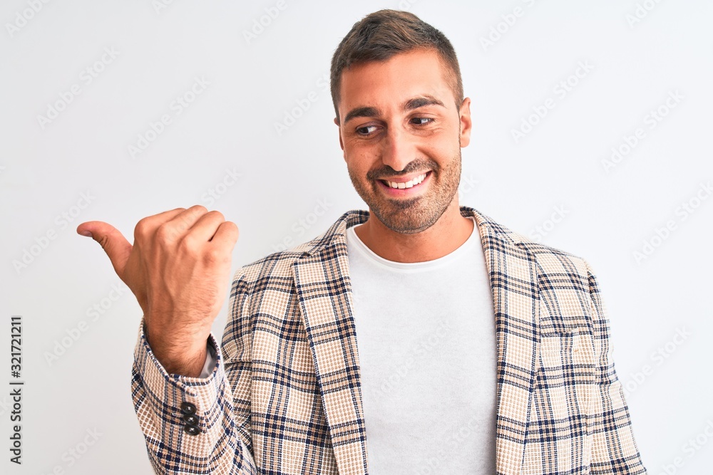 Naklejka premium Young handsome business man wearing elegant jacket over isolated background smiling with happy face looking and pointing to the side with thumb up.