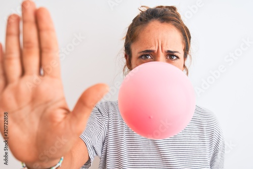Fotografie Young redhead woman chewing gum and blowing hair bubble over white isolated back