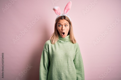 Young beautiful woman wearing easter rabbit ears standing over isolated pink background afraid and shocked with surprise expression, fear and excited face.