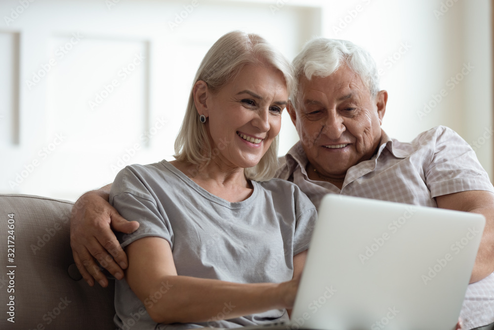 Modern mature couple using laptop relaxing at home Modern mature couple using laptop relaxing at home