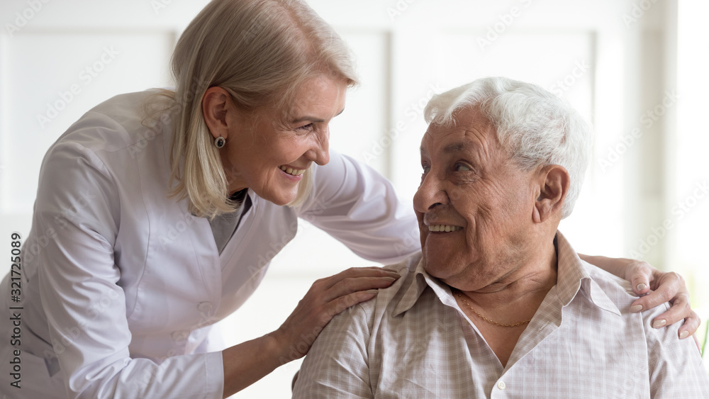 Positive female nurse taking care of senior male patient Positive female nurse taking care of senior male patient