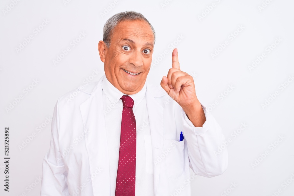 Senior grey-haired scientist man wearing coat standing over isolated white background pointing finger up with successful idea. Exited and happy. Number one. Senior grey-haired scientist man wearing coat standing over isolated white background pointing finger up with successful idea. Exited and happy. Number one.