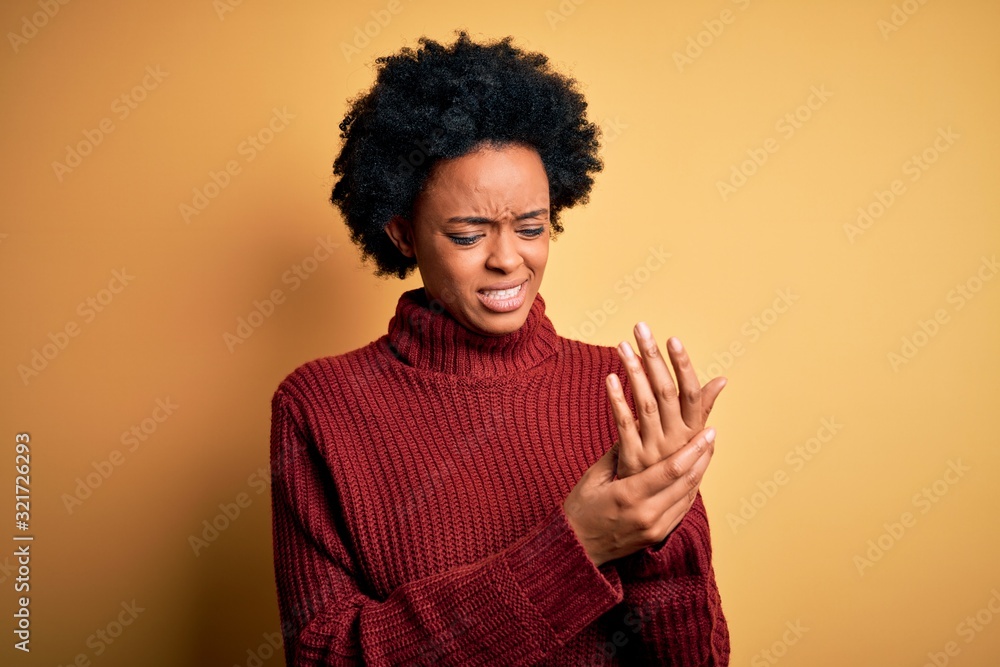 Young beautiful African American afro woman with curly hair wearing casual turtleneck sweater Suffering pain on hands and fingers, arthritis inflammation Young beautiful African American afro woman with curly hair wearing casual turtleneck sweater Suffering pain on hands and fingers, arthritis inflammation
