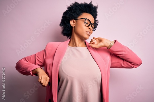 Young beautiful African American afro businesswoman with curly hair wearing pink jacket stretching back, tired and relaxed, sleepy and yawning for early morning